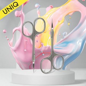 Two stainless steel scissors displayed on a white pedestal with colorful paint splashes and a yellow UNIQ banner above.