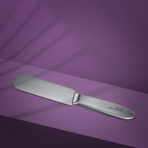 Stainless steel cake knife with a wide blade and rounded tip on a purple background.