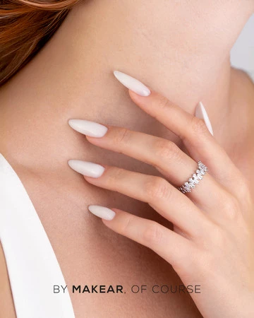 Close-up of a woman’s hand with long white nails wearing a diamond ring on the ring finger; watermark reads 'BY MAKEAR, OF COURSE'.